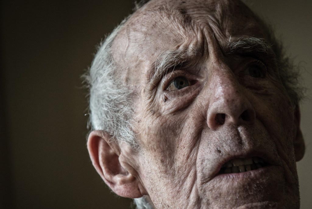 An older man with a neutral expression