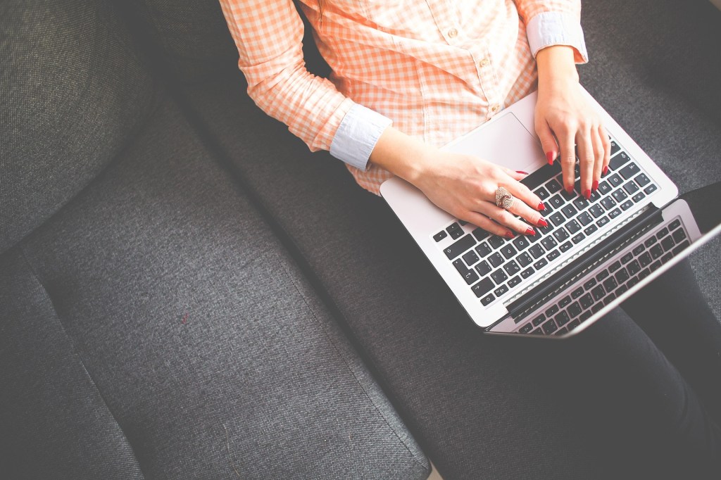 a seated person typing on a laptop, viewed from above.